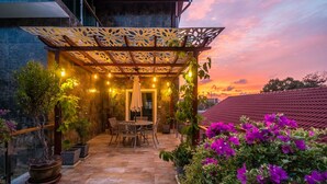 A covered patio area with a pergola, seating, potted plants, and a view of the sunset. - Exclusive Villa Stan with Top Amenities (Kamala)