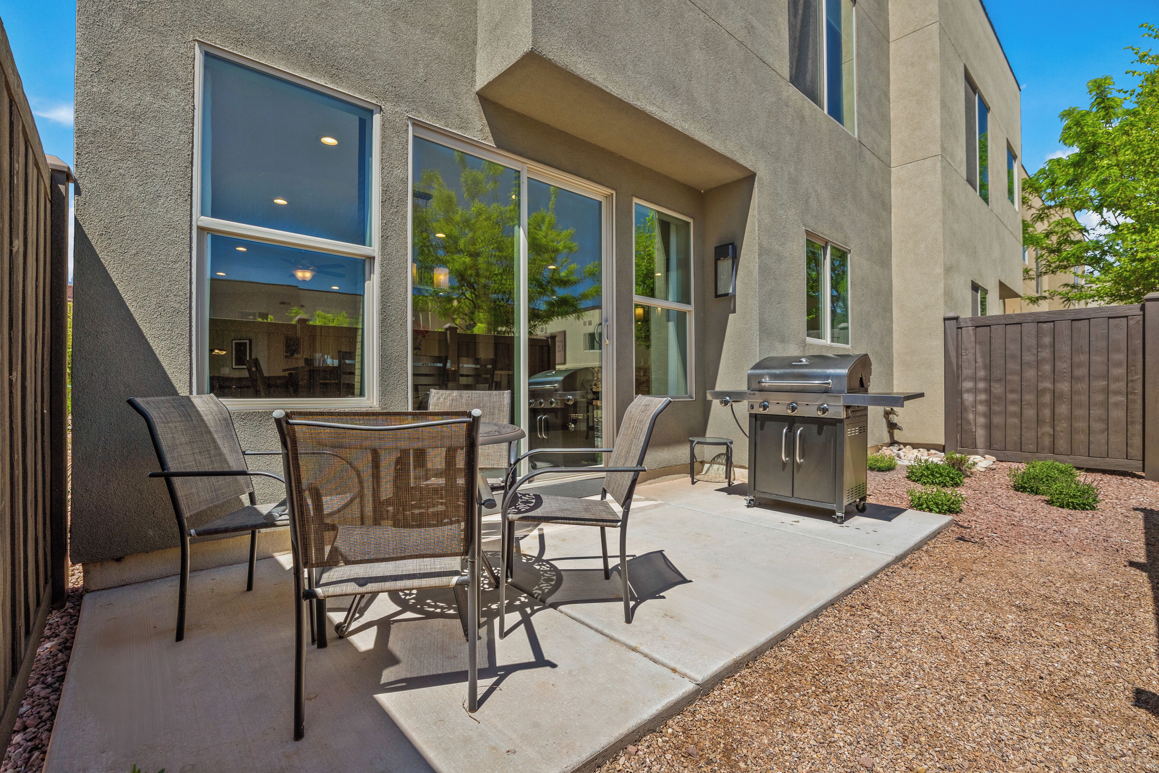 Une terrasse extérieure équipée d’un barbecue, de chaises et offrant une vue sur l’intérieur.