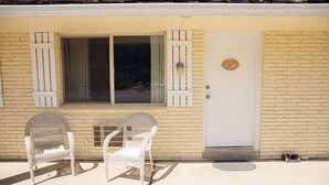 A building with a white door marked with the number 127, two wicker chairs outside, and a window with shutters.