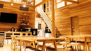 Ein geräumiger Innenraum aus Holz mit hoher Decke, Holzbalken und einer Treppe zu einer oberen Ebene.
