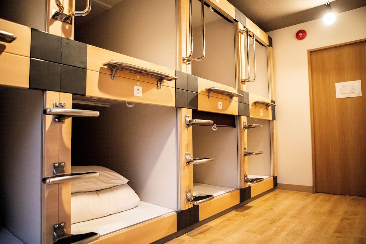 Habitación de hotel con literas, suelo de madera y una puerta con un cartel.