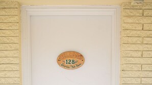 Una puerta blanca con una placa de madera que dice 'WELCOME 128 Licorice Stick Room'.