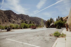 A parking lot with a mountain backdrop, a building with a sloped roof, and a clear sky.