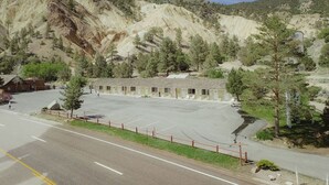 Un motel con un amplio estacionamiento, una carretera al frente y montañas al fondo.