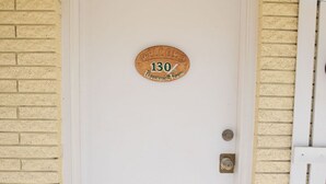 Une porte blanche avec une plaque en bois sur laquelle on peut lire : « Bienvenue, salle 130, Peppermint Room. »