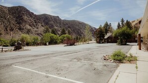 A parking lot with a mountain backdrop, a building with a sloped roof, and a clear sky. - 0131) Candy Suite 131 (Sevier)