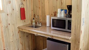 A compact kitchen with wooden walls, a stainless steel refrigerator, a microwave, a sink, and a small trash bin. - 0131) Candy Suite 131 (Sevier)