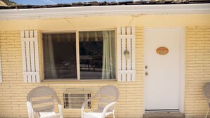 A building with a white door, a window with shutters, and two wicker chairs outside. - 0131) Candy Suite 131 (Sevier)