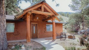 A rustic log cabin with a stone fireplace, a wooden porch, and a clear view of the surrounding forest. - Ponderosa Cabin (Deluxe) (Sevier)