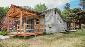 Un chalet rustique doté d’une véranda en bois et d’un espace extérieur aménagé et abrité.