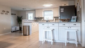 A kitchen with white cabinets, a granite countertop, and a stainless steel refrigerator.