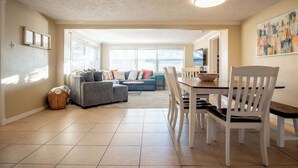 A spacious living room with a dining area, large windows, and a cozy seating arrangement.