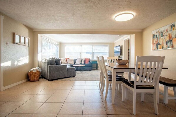 A spacious living room with a dining area, large windows, and a cozy seating arrangement.