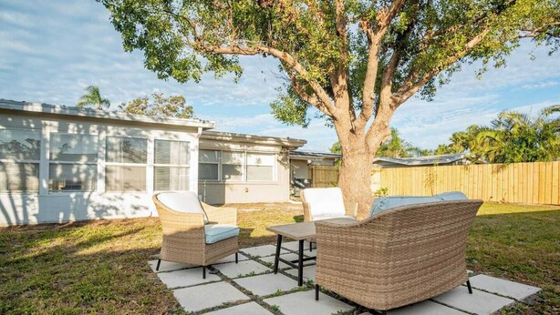 Une cour arrière avec un ensemble de mobilier de jardin, un arbre et une maison en arrière-plan.