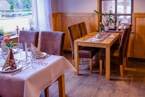 A dining area with a wooden table set for four, surrounded by cushioned chairs. - Gasthaus Heiko Sieb (Wischhafen)