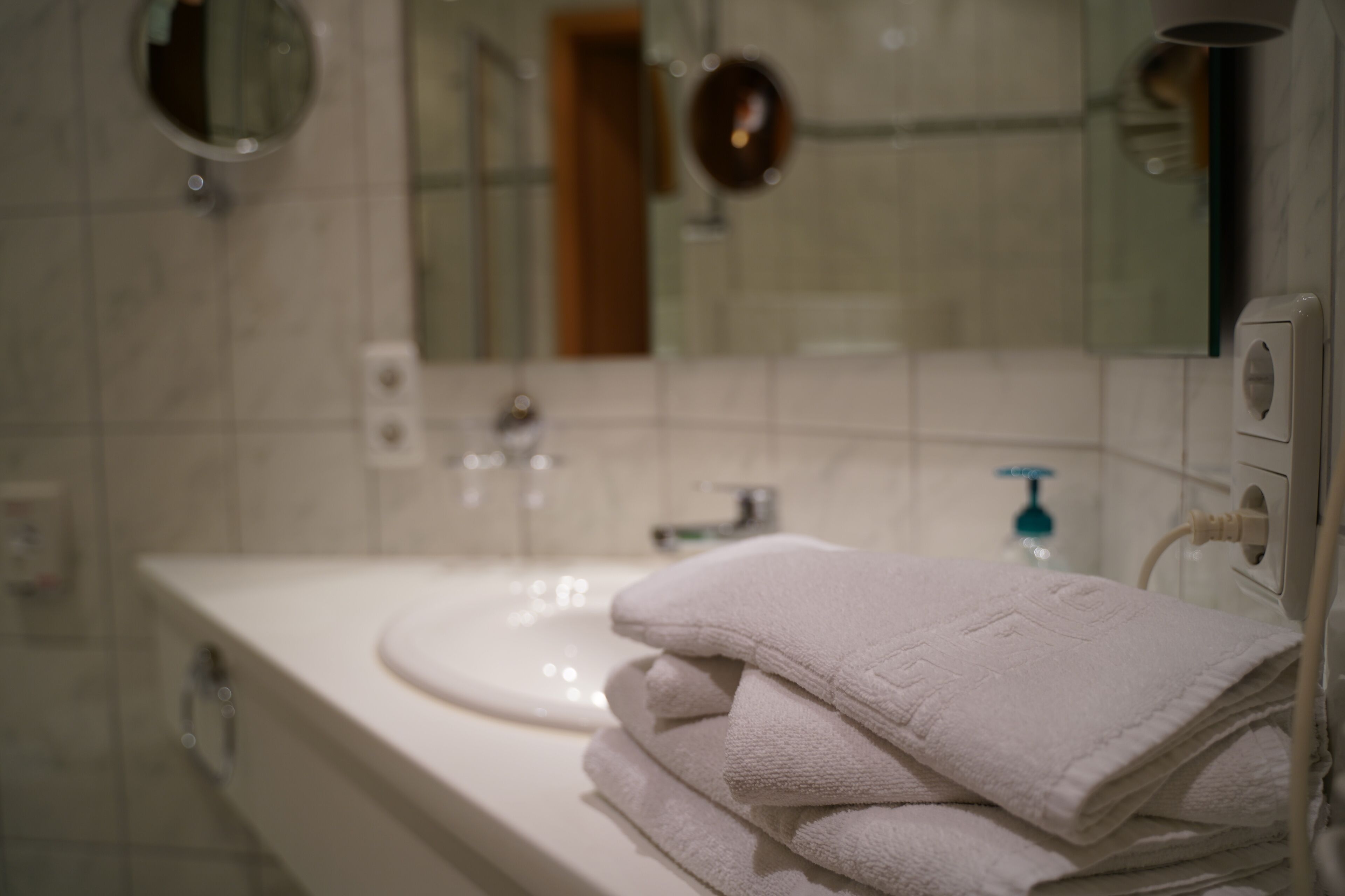 Une salle de bain avec un lavabo, un miroir et des serviettes pliées.
