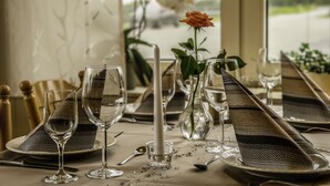 A table set for dining with clear glassware, a vase with a single flower, and patterned napkins. - Gasthaus Heiko Sieb (Wischhafen)