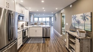 Una cocina moderna con electrodomésticos de acero inoxidable, una isla central y vistas a un balcón.