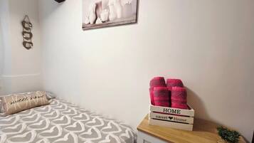 Una camera da letto con un letto, un comodino con un cesto e un quadro appeso al muro.