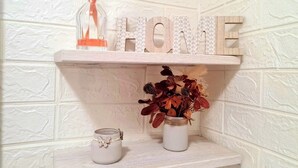 Een plankje met het woord 'HOME' in decoratieve letters en een vaas met gedroogde bloemen.