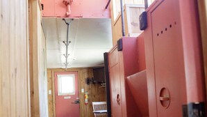 A narrow hallway with wooden walls and a red door at the end.