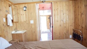 A wooden-paneled room with a bed, a sink, and a mirror.