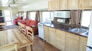 Une cuisine compacte dotée de meubles en bois, d’un four à micro-ondes, d’une cuisinière et d’un coin repas avec une table et des chaises.