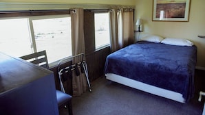 Une chambre à coucher avec un lit, un bureau, une chaise et une fenêtre.
