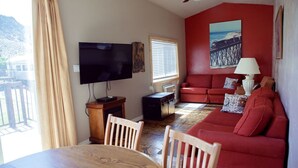 A living room with a red couch, a television, and a painting of a pier. - T-00003) The Sante Fe (Sevier)