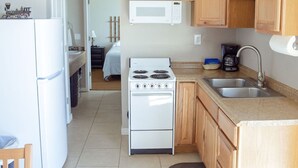 A compact kitchen with wooden cabinets, a white stove, a microwave, and a sink. - T-00003) The Sante Fe (Sevier)