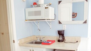 Pieni, käytännöllinen keittiönurkkaus, jossa on mikroaaltouuni, kahvinkeitin ja pieni jääkaappi.