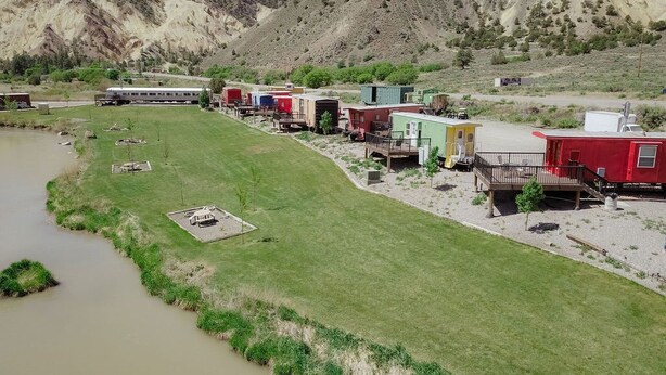 A campground with RVs and cabins near a river, surrounded by hills. - T-0001) Missouri Pacific (Sevier)