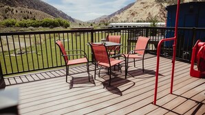 A deck with outdoor seating, a view of a river, and mountains in the background. - T-0001) Missouri Pacific (Sevier)