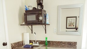 A compact kitchen with a microwave, coffee maker, and a refrigerator. There is a sink with a faucet, a countertop with a dish rack, and a small cabinet. - T-0001) Missouri Pacific (Sevier)