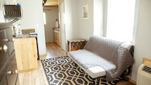 A compact living space with a kitchenette, a bed with a quilted cover, and a patterned rug. - T-008) The Cotton Belt (Sevier)