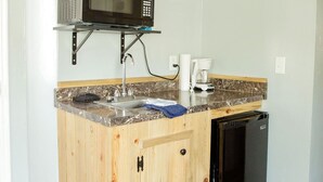 A compact kitchen with wooden cabinetry, a built-in microwave, a sink, and a dishwasher. - T-008) The Cotton Belt (Sevier)