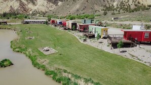A campground with RVs and cabins near a river, surrounded by hills. - T-008) The Cotton Belt (Sevier)