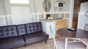 A compact living space with a sofa, a small kitchenette, a dining table, and a microwave. - T-09) Southern Pacific (Sevier)