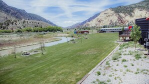 A grassy field with a river, mountains in the background, and a train in the distance. - T-10) Northern Pacific (Sevier)