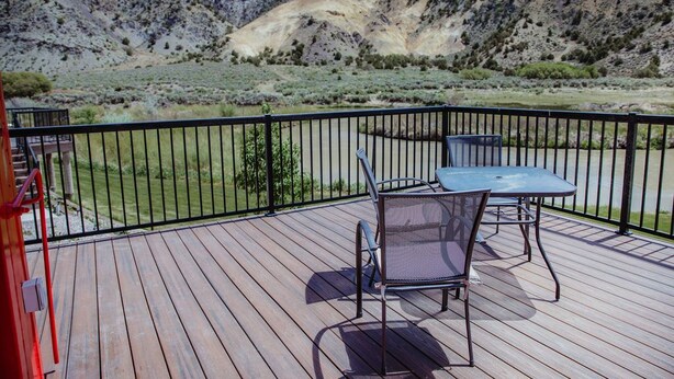 A wooden deck with a table and chairs, overlooking a mountainous landscape. - T-10) Northern Pacific (Sevier)