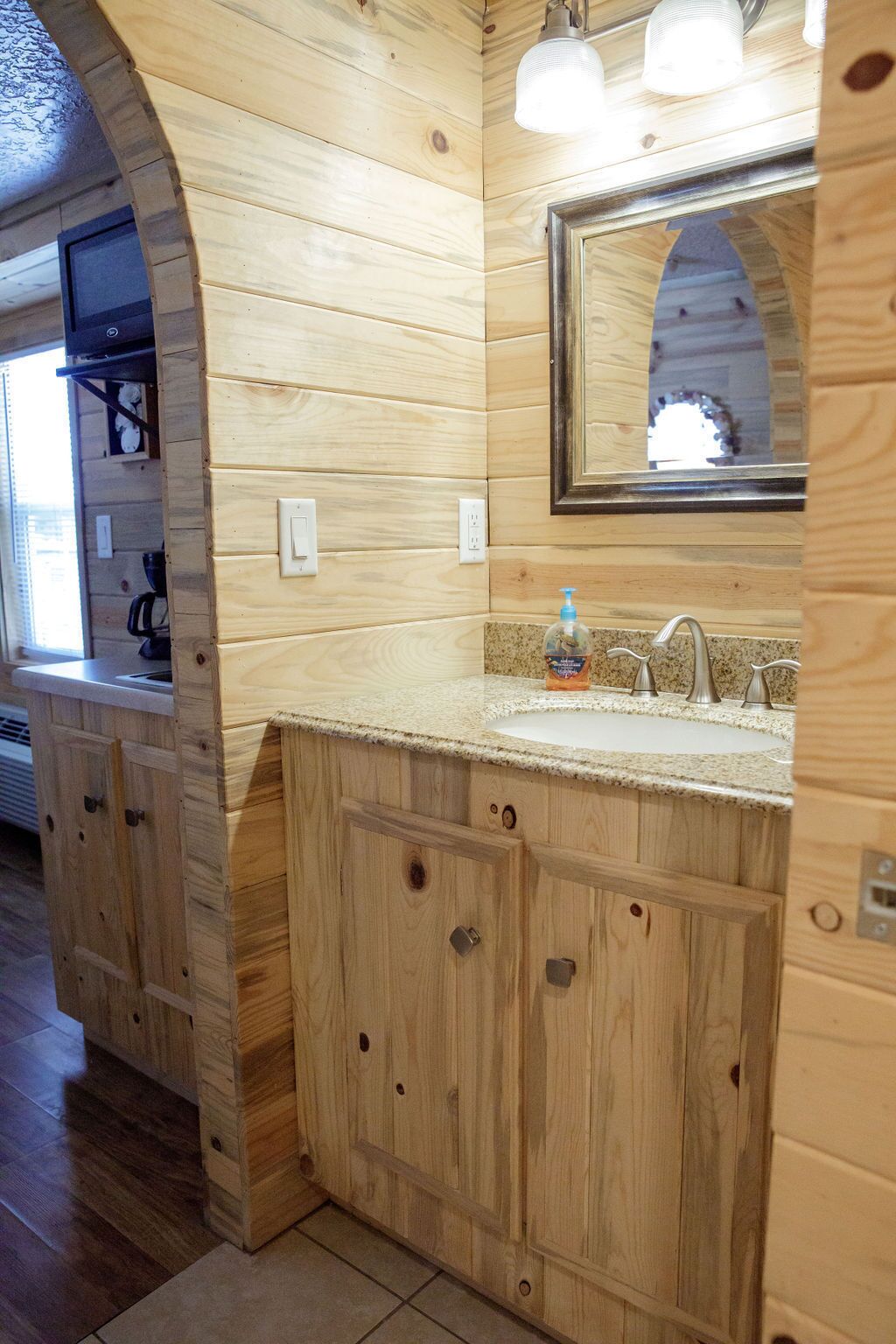 A wooden interior with a sink, mirror, and cabinets.