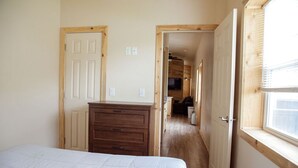 A bedroom with a bed, a wooden dresser, and a window. - T-11) Great Northern (Sevier)