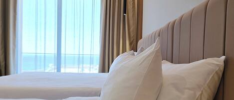 Una habitación de hotel moderna con una cama grande, un cabecero y vistas a la ciudad desde la ventana.