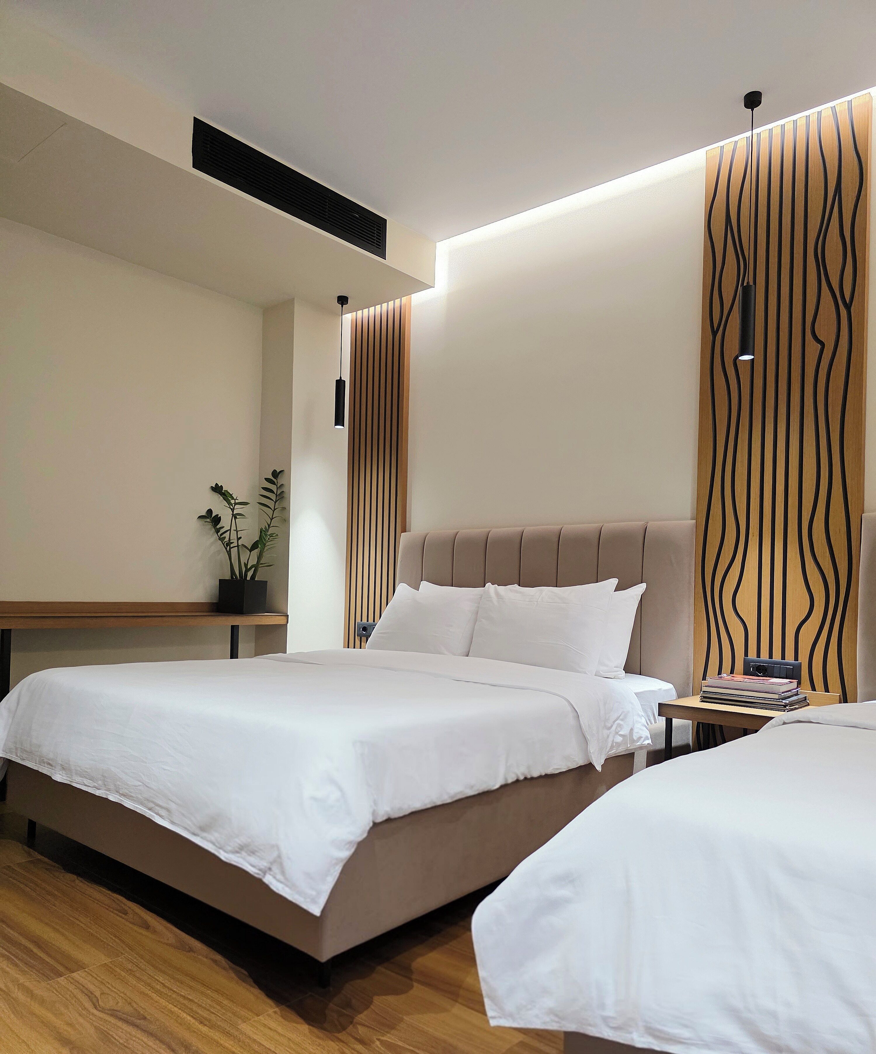 Une chambre d’hôtel moderne avec un grand lit, des tables de chevet et une petite table avec des livres.