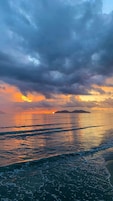Une plage avec des vagues et un coucher de soleil.
