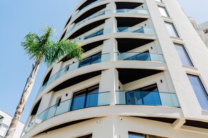 Un edificio de varios pisos con balcones y grandes ventanales.