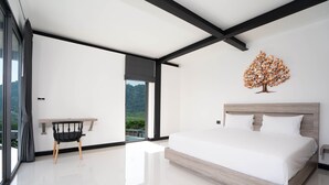 Een moderne slaapkamer met een groot bed, een bureau en uitzicht op groen.