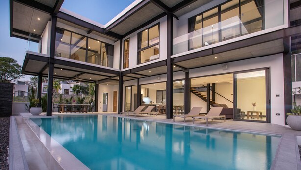 Een modern huis met een zwembad, meerdere balkons en een goed verlicht interieur.