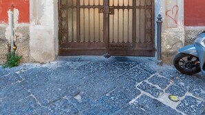 A building entrance with a large, ornate metal gate and a small motorcycle parked nearby. - Montemiletto a Panoramic Nest by Napoliapartments (Naples)