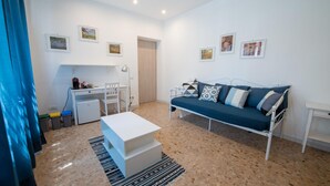 A modern living room with a sofa, a coffee table, a desk with a lamp, and a door leading to another room. - Casa Rosa Beige e Blu (Rome)